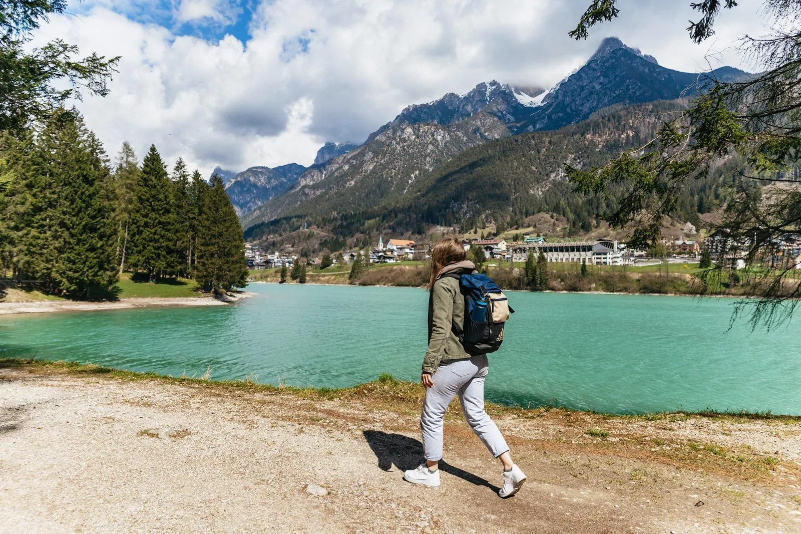 Hiker on the shore of a turquoise alpine lake near Cadore