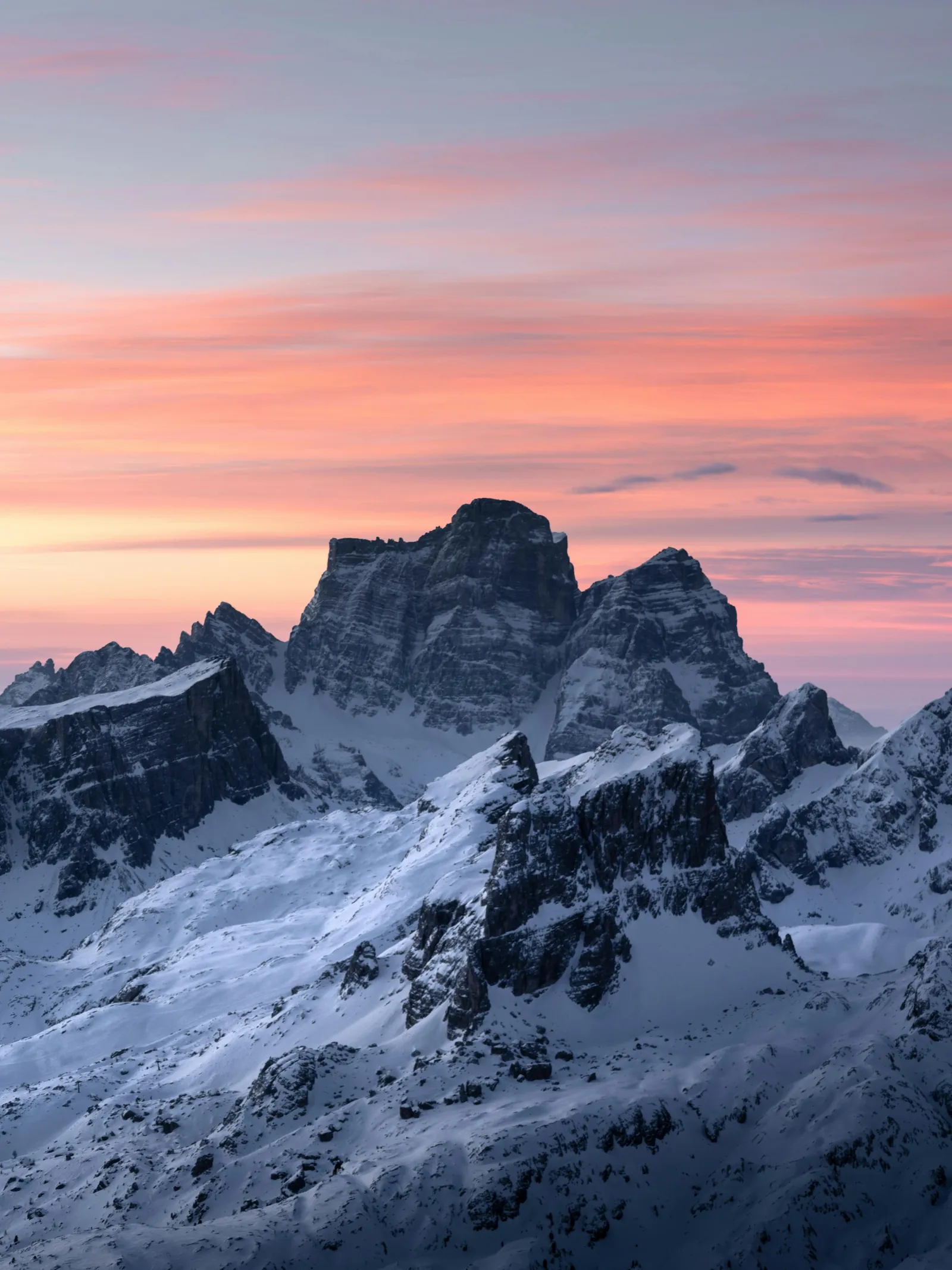 Snow-streaked Dolomites summit under a pink dawn sky