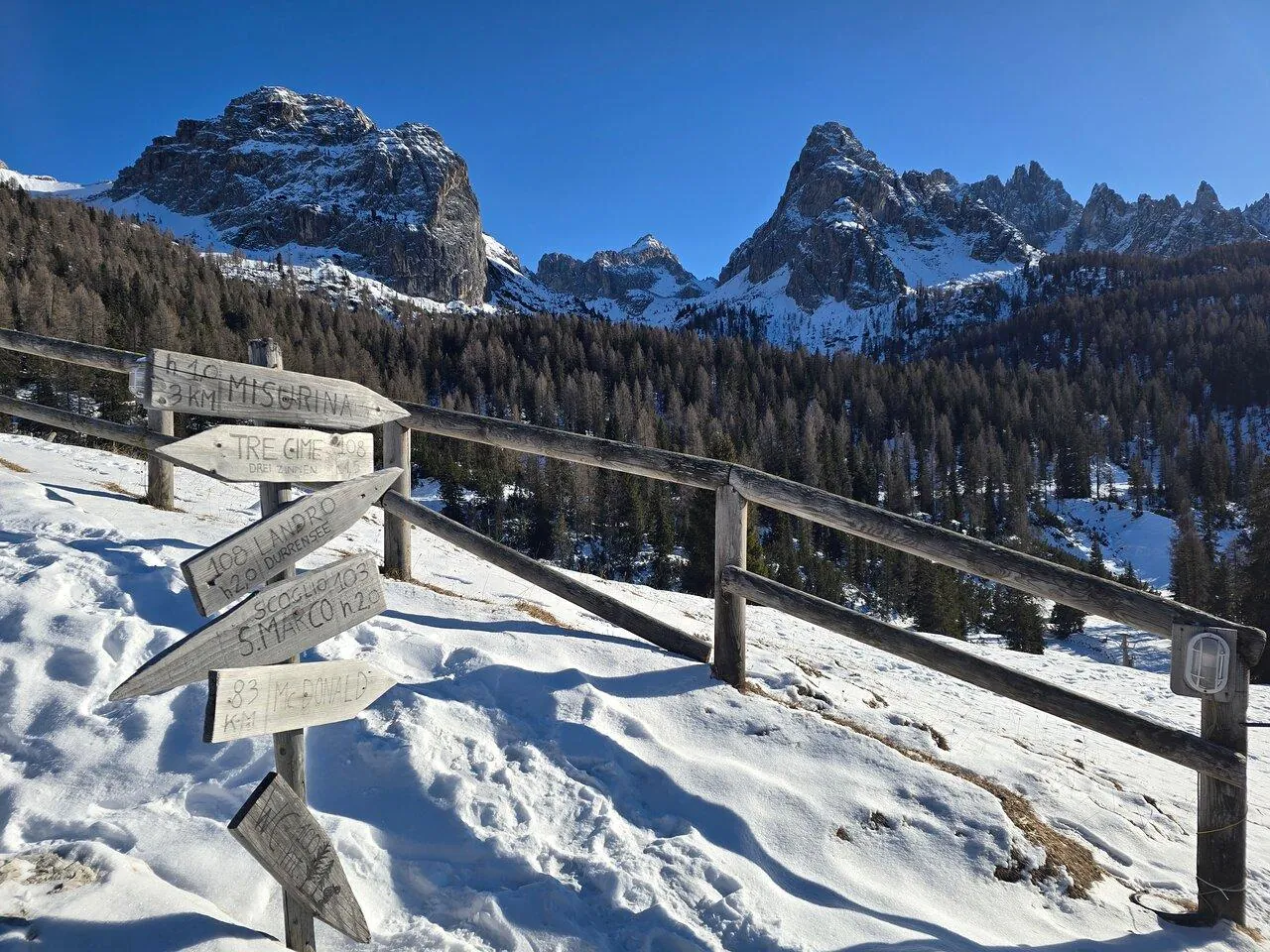 Snowy viewpoint with signposts above the Cadore valley