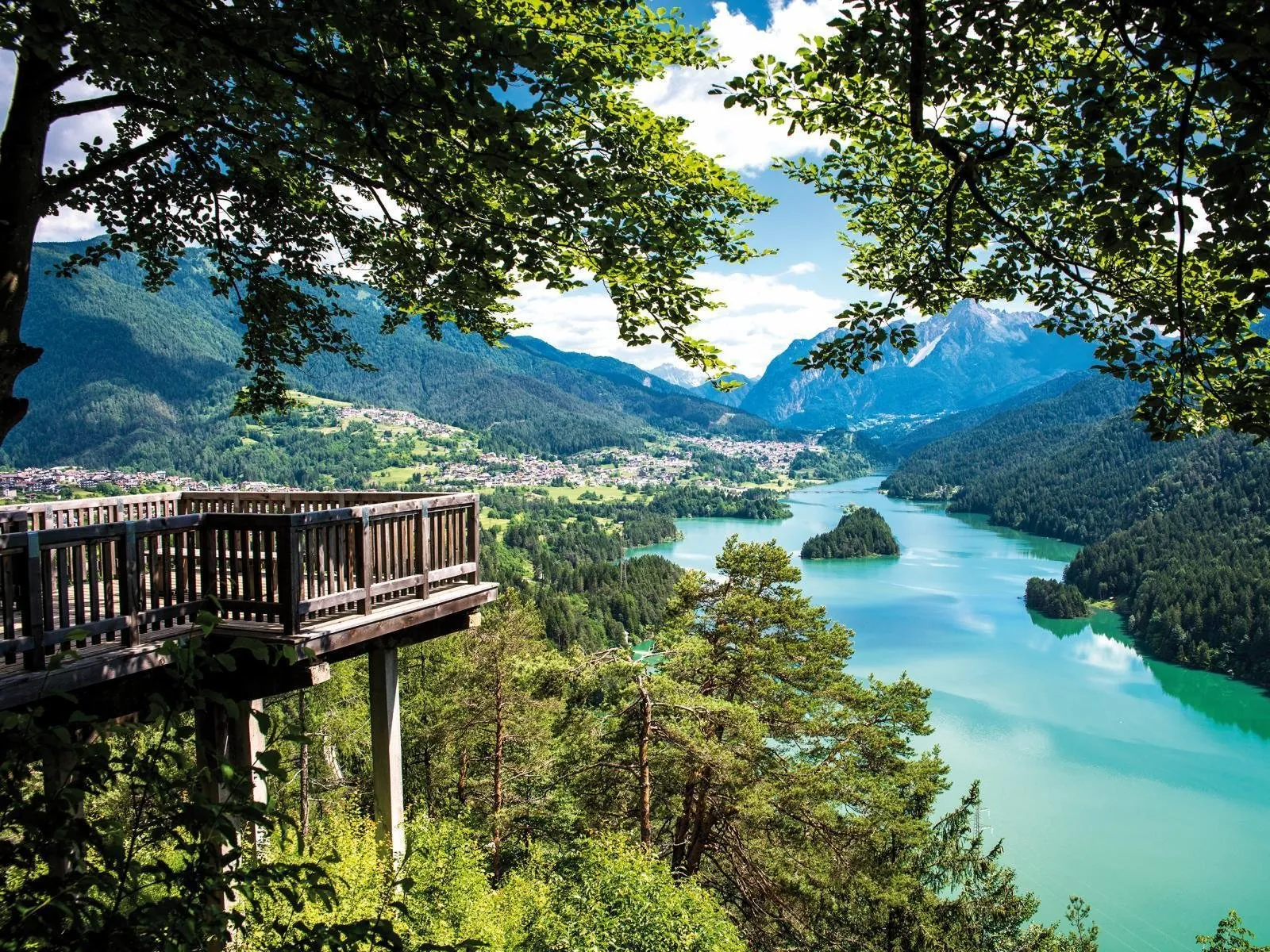 Turquoise reservoir seen from a wooden viewing platform in the Cadore valley