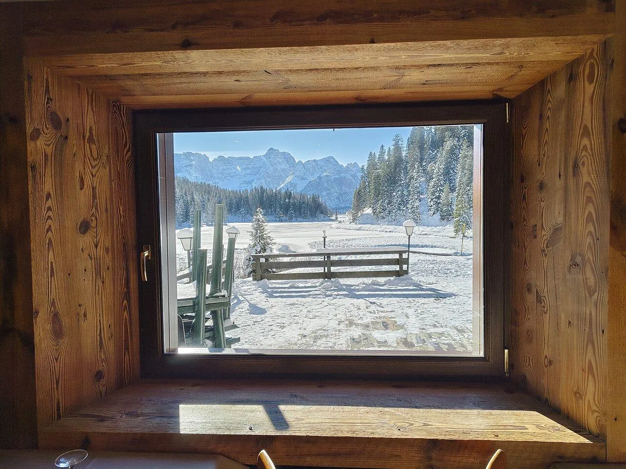 Snow-covered Lake Misurina framed through a wooden hut window